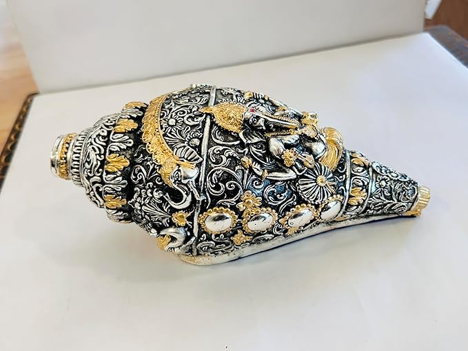 Decorative shell with intricate silver and gold patterns on a white surface