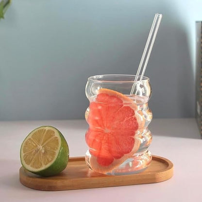 Clear glass with grapefruit and lime on a wooden tray against a light blue background