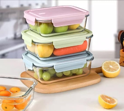 Set of glass food storage containers with colorful lids on a kitchen counter.