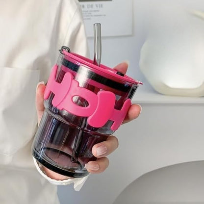 Clear tumbler with pink lid and straw held by a hand against a neutral background
