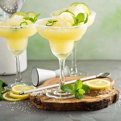 Three margarita glasses with lemon slices and mint leaves on a wooden board.