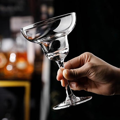 Hand holding a clear martini glass against a blurred bar background