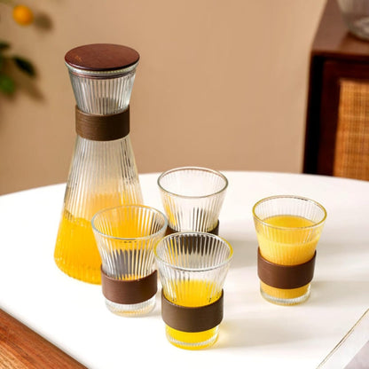 Set of glass carafe and glasses with brown bands on a white surface