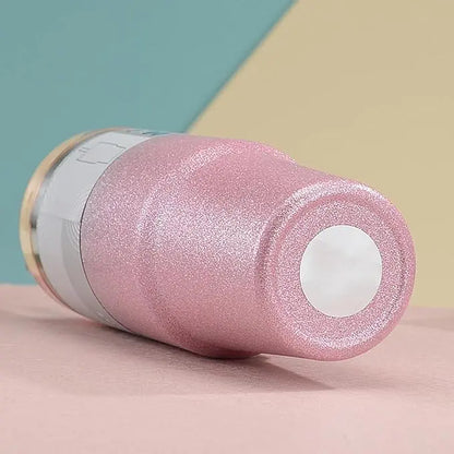 Pink glittery cylindrical object with a white label on a pink surface