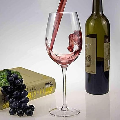 Wine being poured into a glass with a bottle and grapes on a white background
