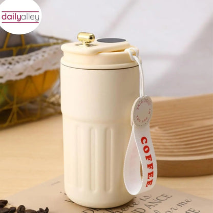 White ceramic coffee mug with a strap labeled 'COFFEE' on a wooden surface.