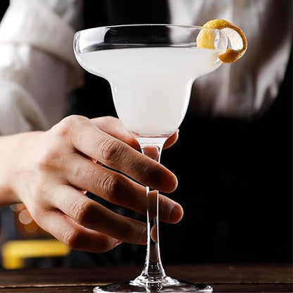 Cocktail in a martini glass with a lemon twist held by a hand against a dark background