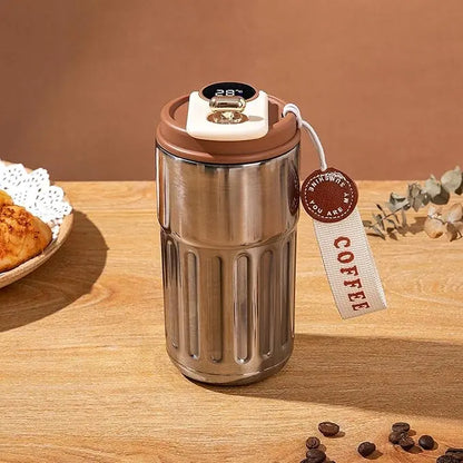 Stainless steel coffee tumbler with brown lid on a wooden surface, featuring a 'COFFEE' tag.