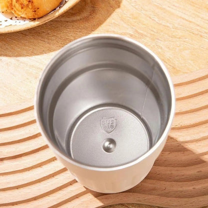 Silver metal cup with lid on a wooden surface