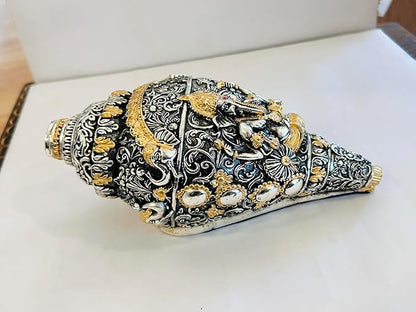 Decorative shell with intricate silver and gold patterns on a white surface
