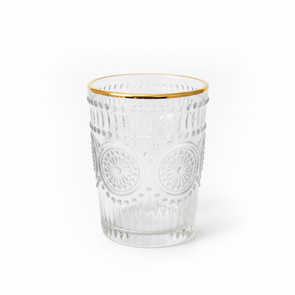 Clear glass tumbler with gold rim on a white background