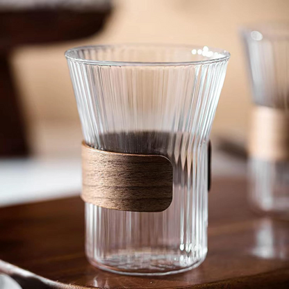 Clear glass tumbler with wooden band on a wooden surface