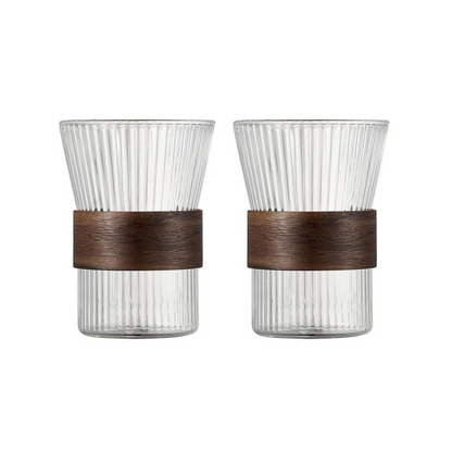 Two clear glass tumblers with brown rubber bands on a white background