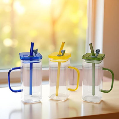 Three colorful drinking cups with lids and straws on a table.