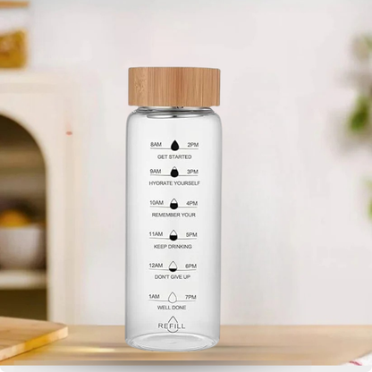 Clear water bottle with bamboo cap and time markings on a wooden surface